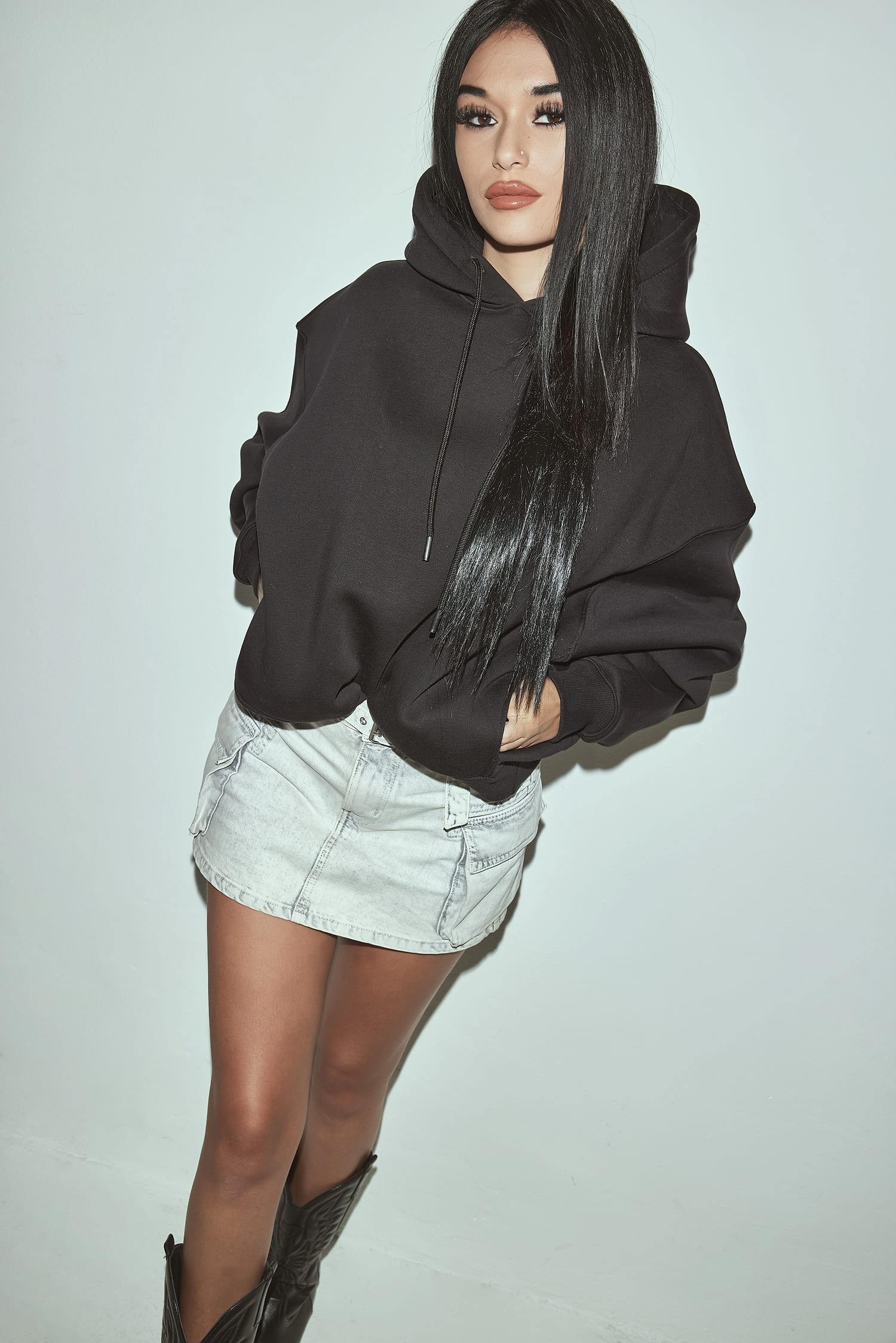 Modella Sassolini con hoodie oversize nero, minigonna denim e stivali — capo protagonista della collezione